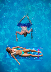 Couple relaxing on a lilo mattress at the swimming pool