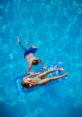 Couple relaxing on a lilo mattress at the swimming pool