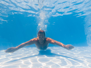 man swimming underwater in the swimming poll