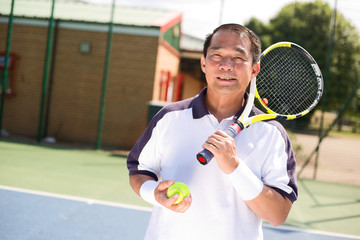 filipino man holding a tennis racket and ball