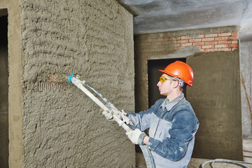 Plasterer spraying plaster on wall