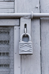 Gray lock on a gray painted wooden door.