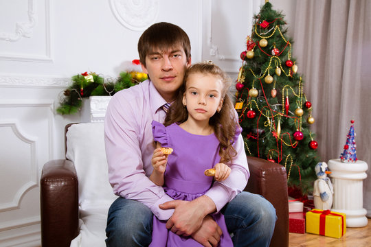 Father and the daughter on Christmas, sitting near a christmas fir-tree