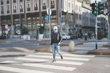Young handsome caucasian man walking through pedestrian crossing, wearing an alien mask - surreal, eccentri concept
