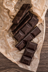 Dark Chocolate Bars on Crumbled Paper and Wooden Table