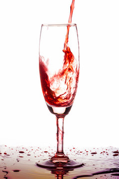 Red wine poured in a glass on white backgroubd.