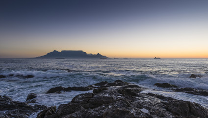 Cape Town Table Mountain's iconic flat top seen from Blouberg Strand in South Africa during sunset.