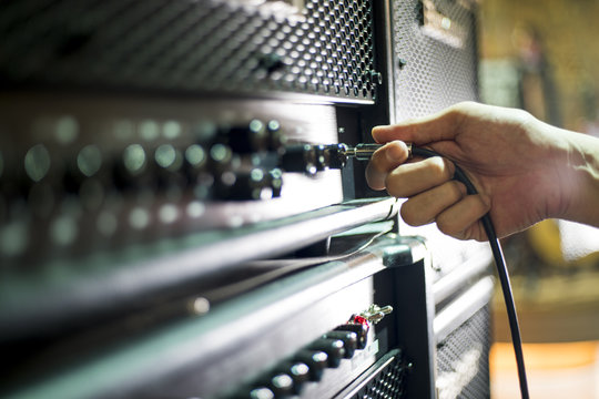 Closed up hand holding jack plug-in to the guitar amplifier