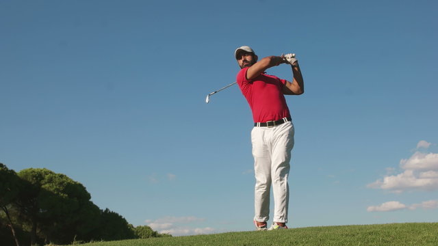 young healthy golfer hitting golf shot with club on course
