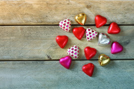 top view image of colorful heart shape chocolates on wooden table. valentine's day celebration concept

