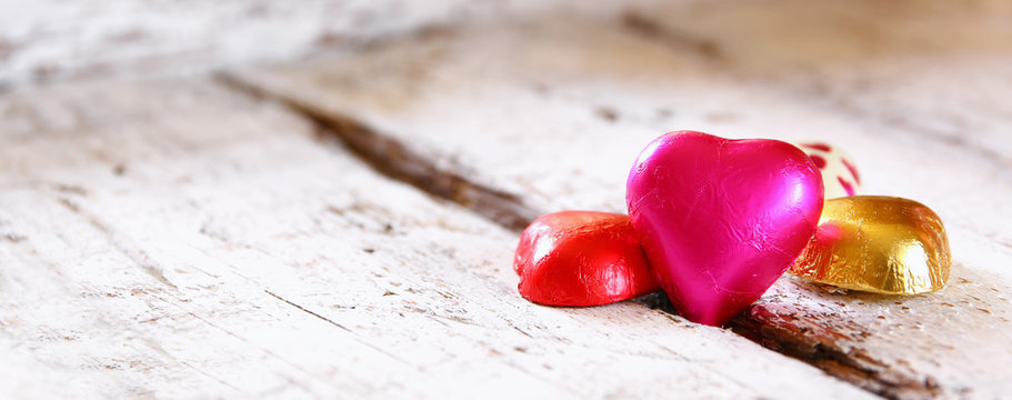 website banner image of colorful heart shape chocolates on wooden table. valentine's day celebration concept
