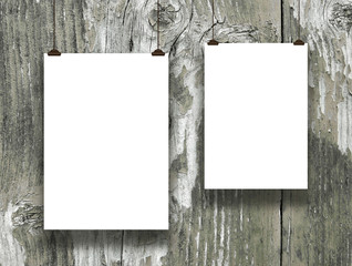 Close-up of two hanged paper sheet frames with clips on weathered wooden boards background