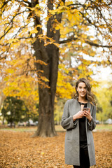 Young woman with mobile phone in autumn park