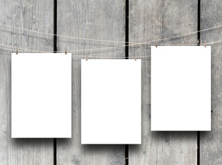 Three paper sheet frames hung by clothes pin on grey wooden boards background
