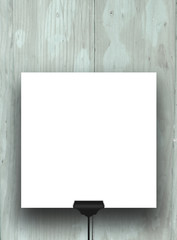 Close-up of one hanged square frame with black clip on blue wooden boards background