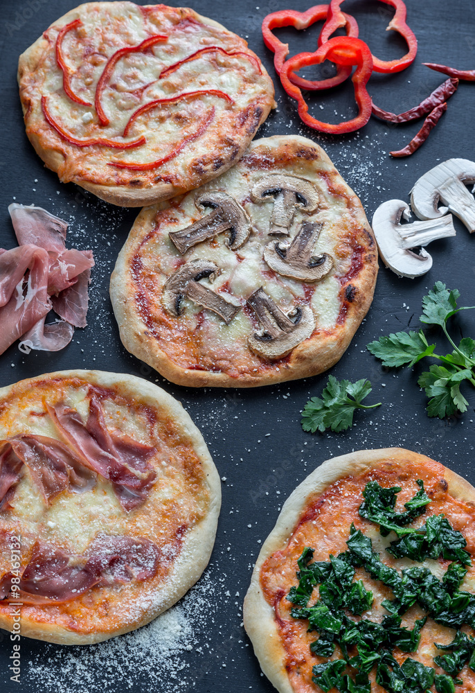 Wall mural mini pizzas with various toppings on the wooden board