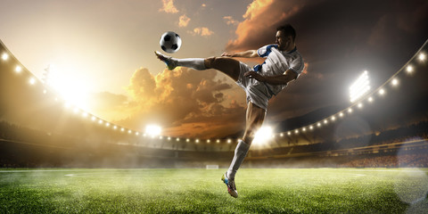 Soccer player in action on sunset stadium panorama background