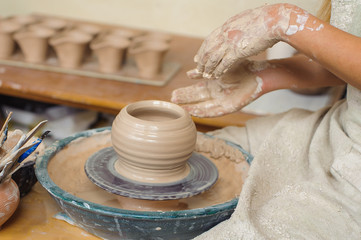 hands of a potter, creating an earthen jar on the circle