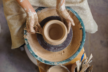 hands of a potter, creating an earthen jar on the circle