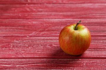 Ripe apple on a red wooden table