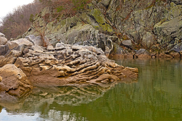 Whimsical rock formation in Potomac River at Great Falls Park in Maryland, USA. River water reflections and symmetry created by rock formation.