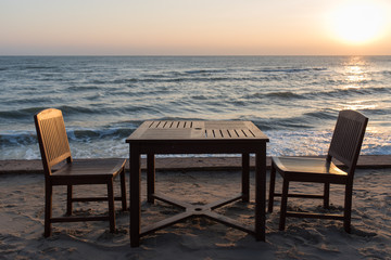 Fototapeta na wymiar Wooden chairs on the beach at sunrise with a tropical sea background