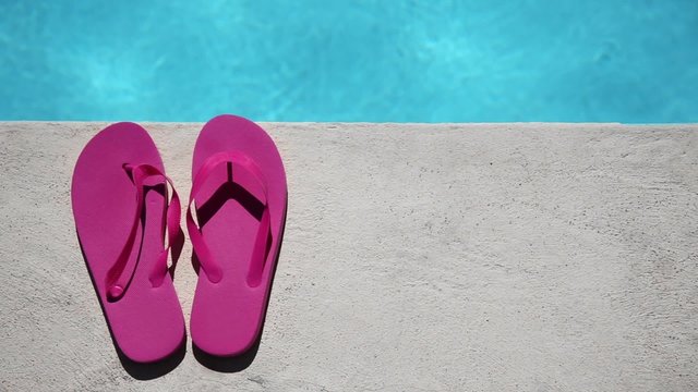Pink slippers near swimming pool at poolside