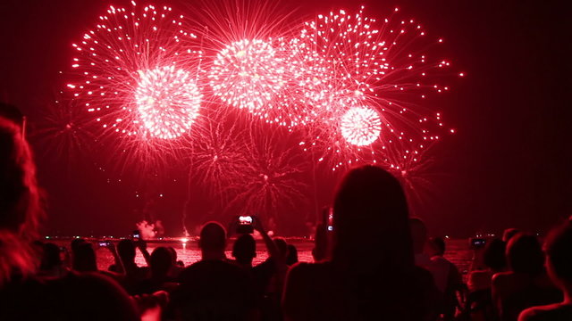 Spectators with smartphones watching fireworks