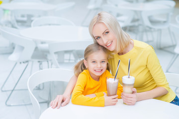 Happy mother and daughter sitting in the cafe 