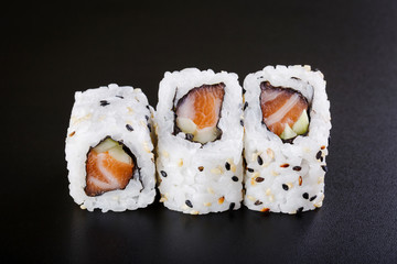 fresh sushi roll with salmon and cucumber, on black backgorund