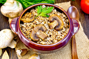 Buckwheat with champignons in clay bowl on table