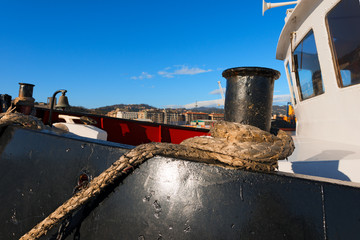 Ship Moored With Old Rope in a Harbor / Detail of the ropes of a black, red and white tugboat moored in the harbor