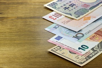 Banknoten großer Volkswirtschaften auf Holzhintergrund