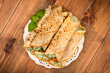 Pancakes filled  with spinach and cheese  on the wooden surface.