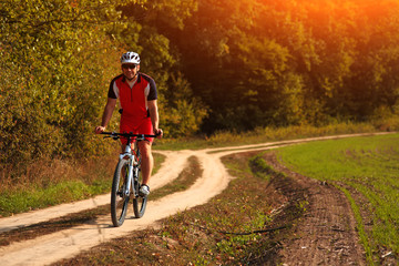 Naklejka premium Cyclist with His Bike on the Autumn Meadow