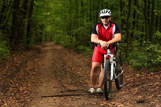 Bicyclist with His Bicycle in the Summer Forest