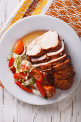 Sliced roasted turkey breast and fresh vegetables closeup. vertical top view
