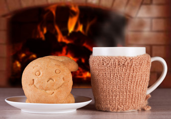 Hot drink with buns in the form of smiles to warm and positive mood on the background of a blazing fire in the oven