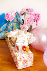 Запакованные подарки на день рождения ребенка и открытки на фоне букета пионов