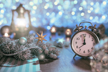 Fototapeta na wymiar Old alarm clock showing five to midnight and glittering decorati