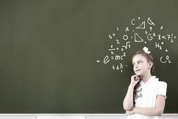 Thoughtful girl standing at blackboard