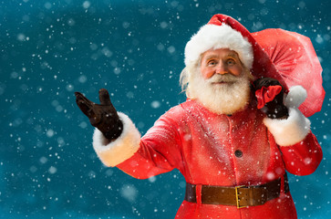 Real Santa Claus, carrying big bag full of gifts to children /  Merry Christmas & New Year's Eve concept / Closeup on blurred blue background. © Romario Ien