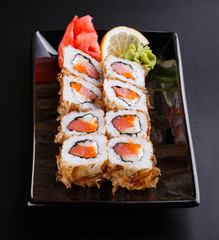fresh sushi roll with smoked salmon, on black dish