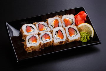 fresh sushi roll with smoked salmon, on black dish
