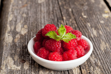 Ripe sweet raspberries in bowl on table close-up