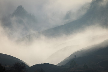 Silhouette of a man in a fog against the backdrop of mountain sl