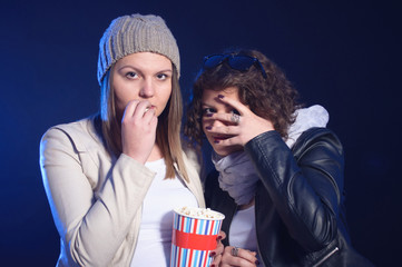 Naklejka premium Two girls are watching horror movie in cinema