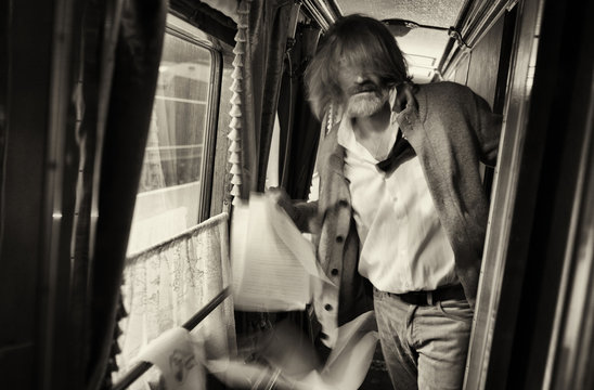 The gray-haired man in a shirt and jacket letter throws his former favorite in the train. Motion blur.