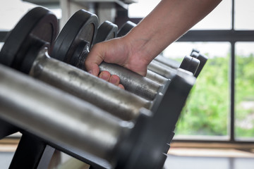 Fototapeta na wymiar strong man's hand takes a heavy dumbbell in gym