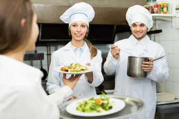 Waitress taking dish from kitchen